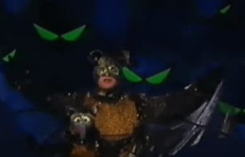 Gonzo and Jason Alexander dressed as bats. Pairs of green bat eyes float in the background.